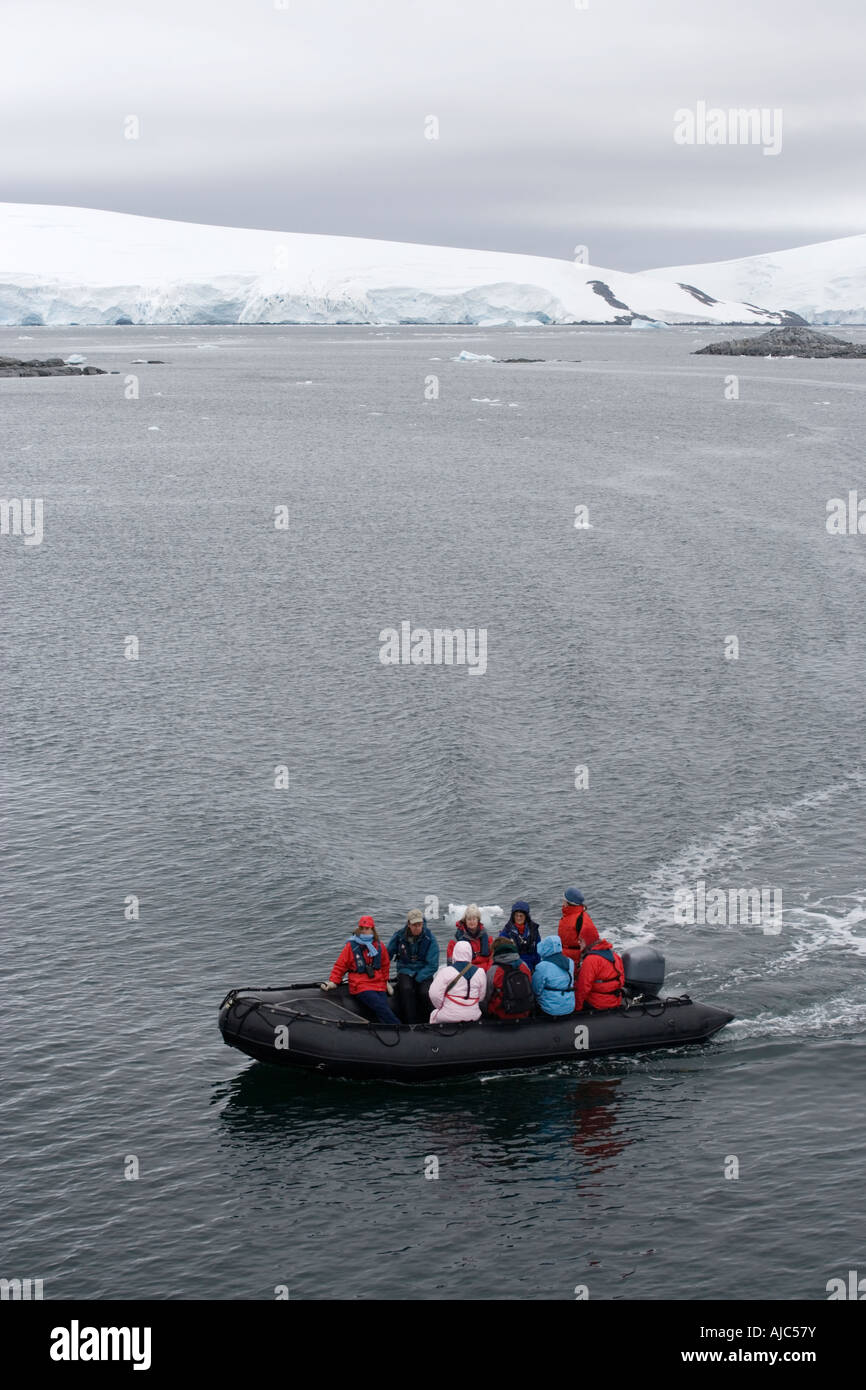 Blick auf Touristen in ein Schlauchboot mit einem Eisberg im Hintergrund - High Angle View Stockfoto