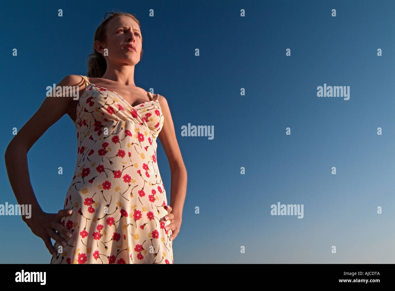 Junge Frau gegen ein blauer Himmel mit den Händen an ihren Hüften auf der Suche in den Big Blue Yonder Schuss aus einem niedrigen Winkel Taille bis Stockfoto