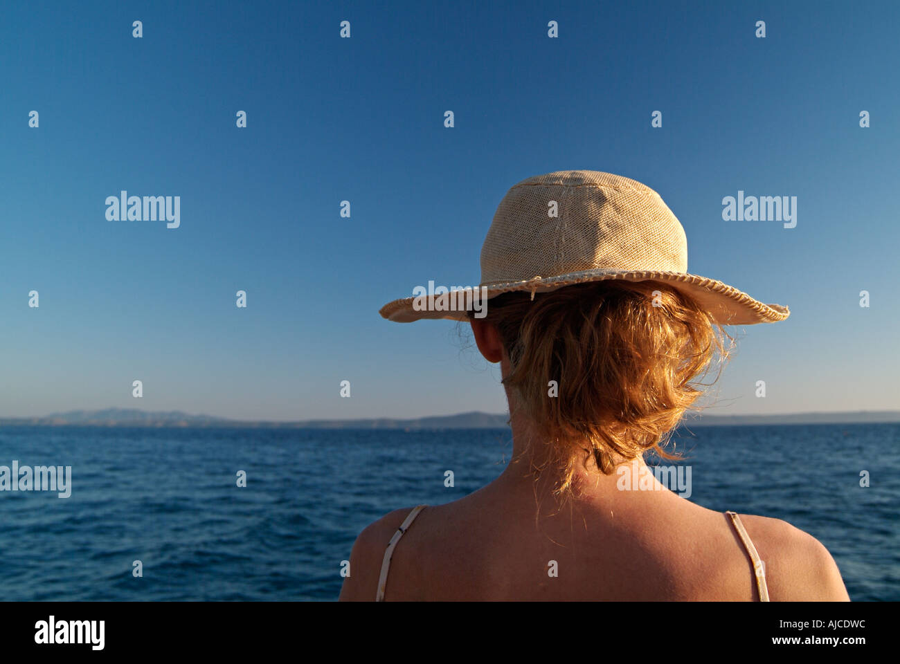 Junge Frau in ein Sonnenhut aus über das Meer auf der Suche Stockfoto