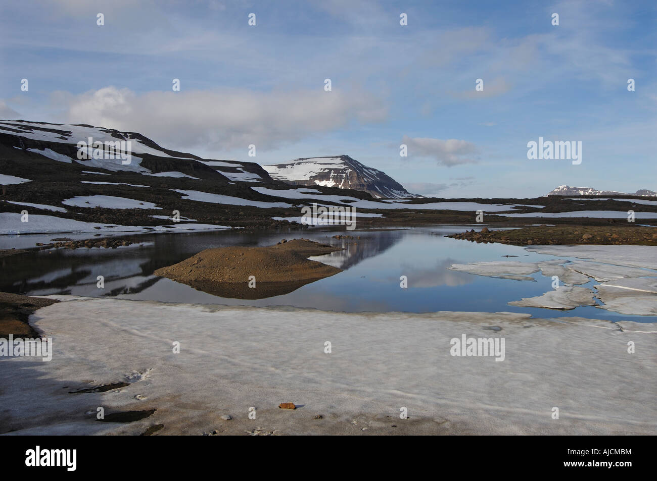 Teilweise noch gefroren Schmelzwasser Pool und den Berg Bjolfur im Bereich von Fjardarheidi in der Nähe von Seydisfjordur East Island Stockfoto