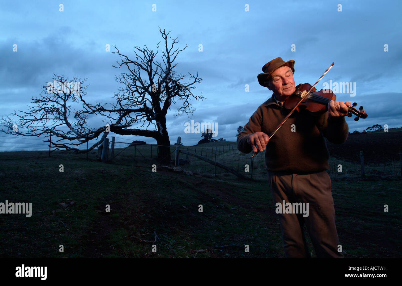 Landwirt spielen Violine in der Abenddämmerung Stockfoto