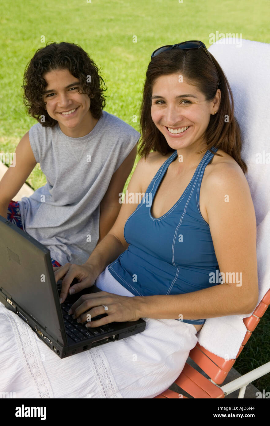 Mutter sitzt auf der Sonnenliege, mittels Laptop im Freien mit Sohn (13-15), Porträt. Stockfoto