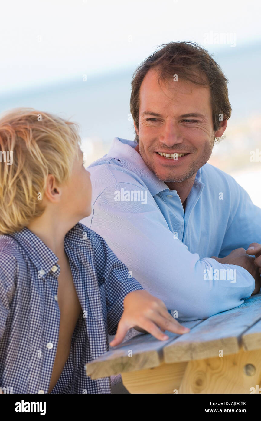 Vater und Sohn am Strand sitzen Stockfoto