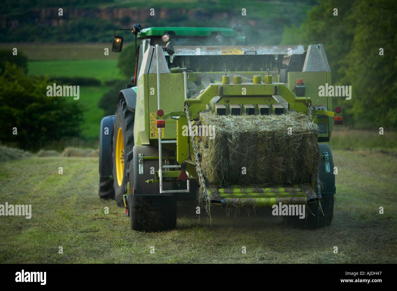 Heuernte im Sommer mit Traktor und Pressen Stockfoto