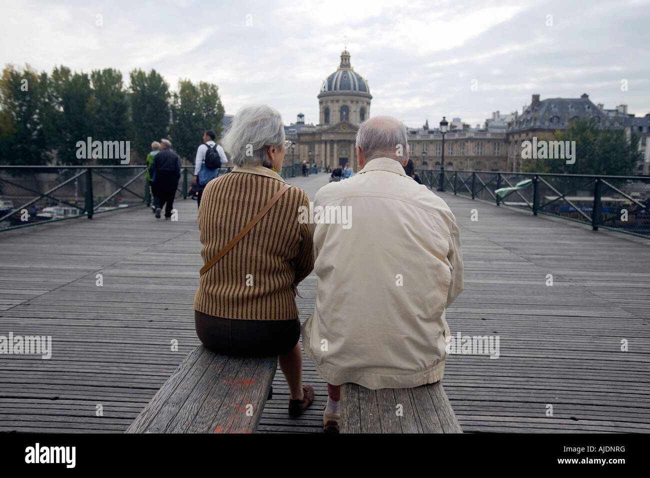 Ein paar sitzt auf einer Bank auf der Pont Brücke des Arts mit Blick auf das Institut de France Academie Francaise Stockfoto