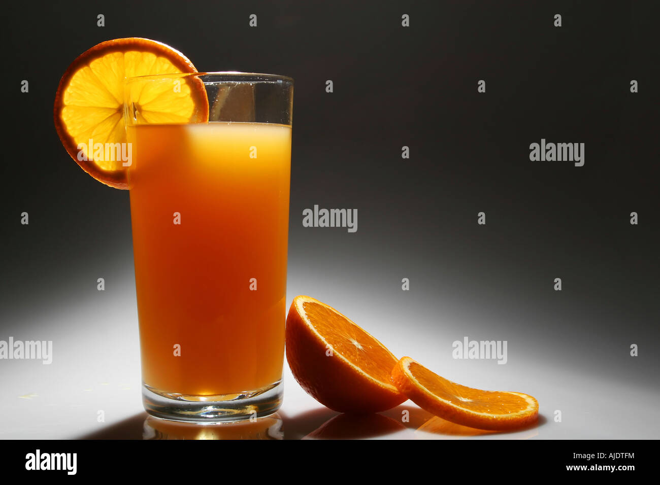 Ein Glas Orangensaft mit einer Scheibe Orange beleuchtet von hinten und oben Stockfoto