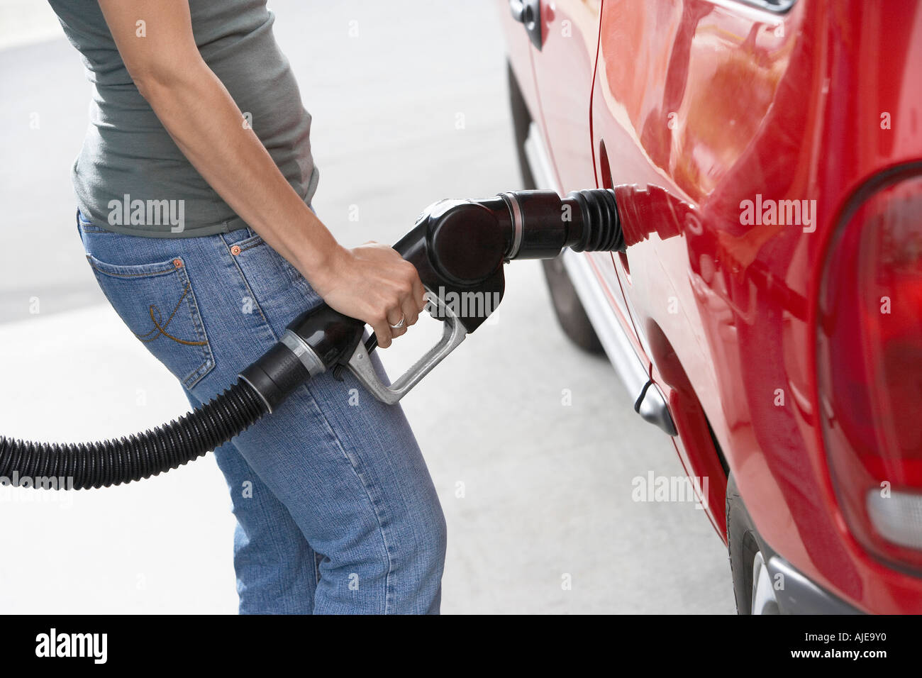 Junge Frau füllt sich Auto mit Gas, Mittelteil Stockfoto