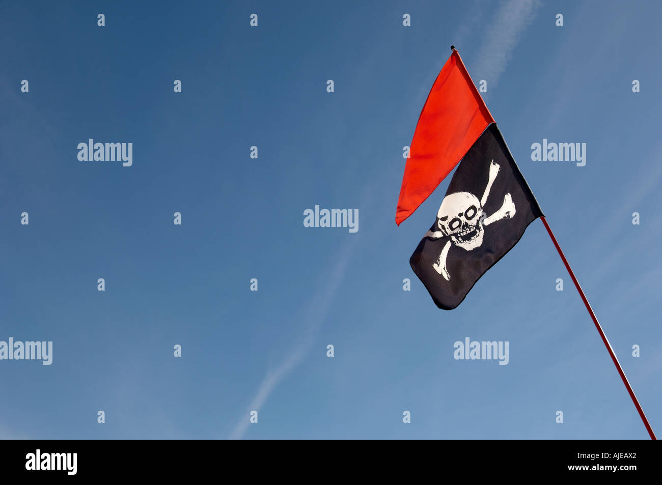 Totenkopf Flagge und rote Fahne gegen blauen Himmel Stockfoto
