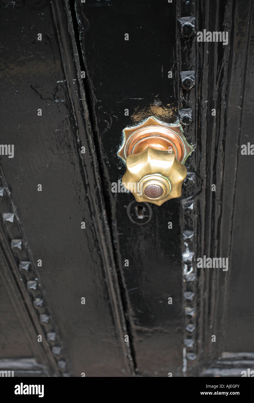 Schwere schwarze Tür mit einem Messing-Knopf. Stockfoto