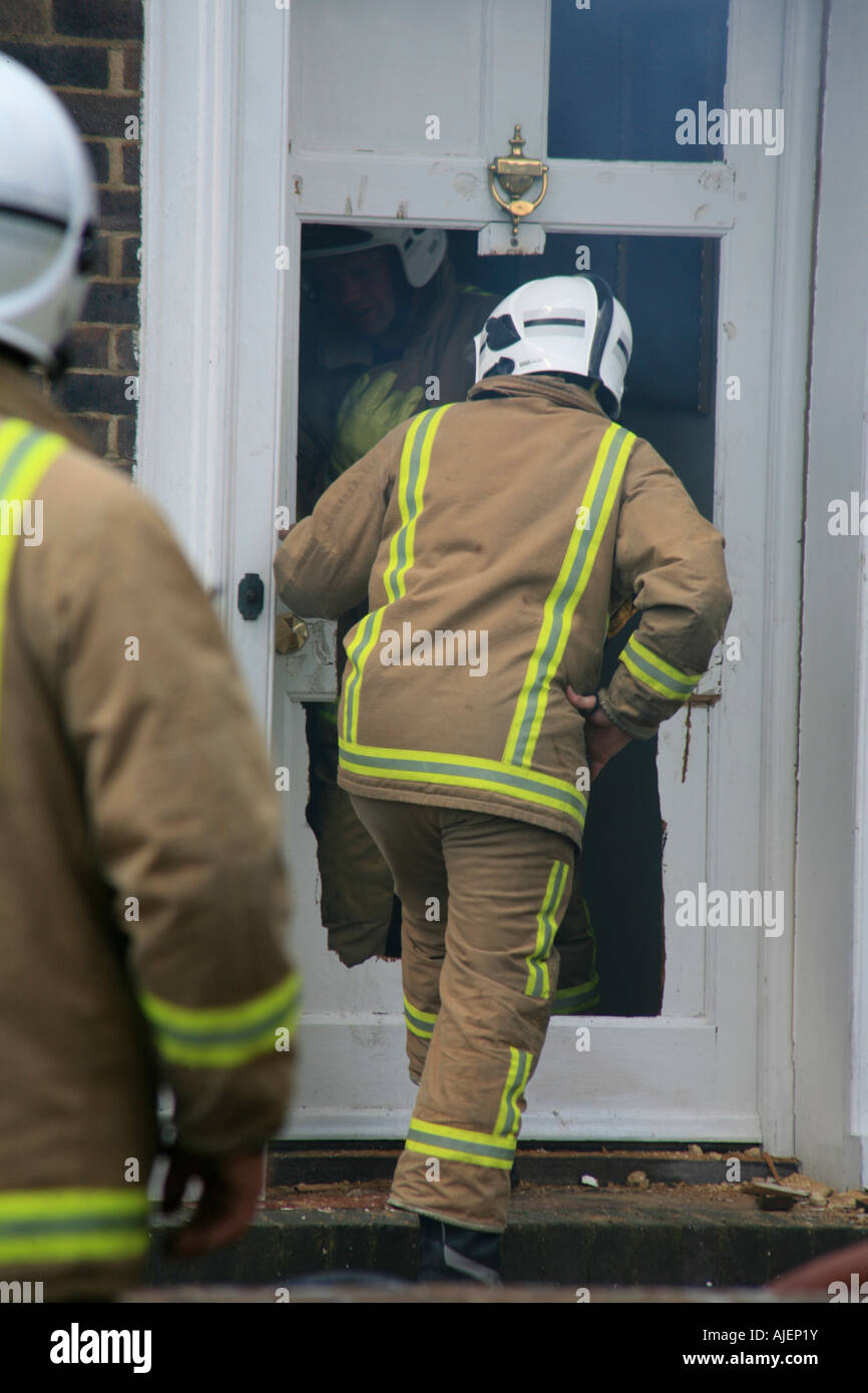 Feuerwehrleute eine Haustür umzuwerfen, Zugriff auf eine Housefire in Tunbridge Wells Kent England Vereinigtes Königreich Stockfoto