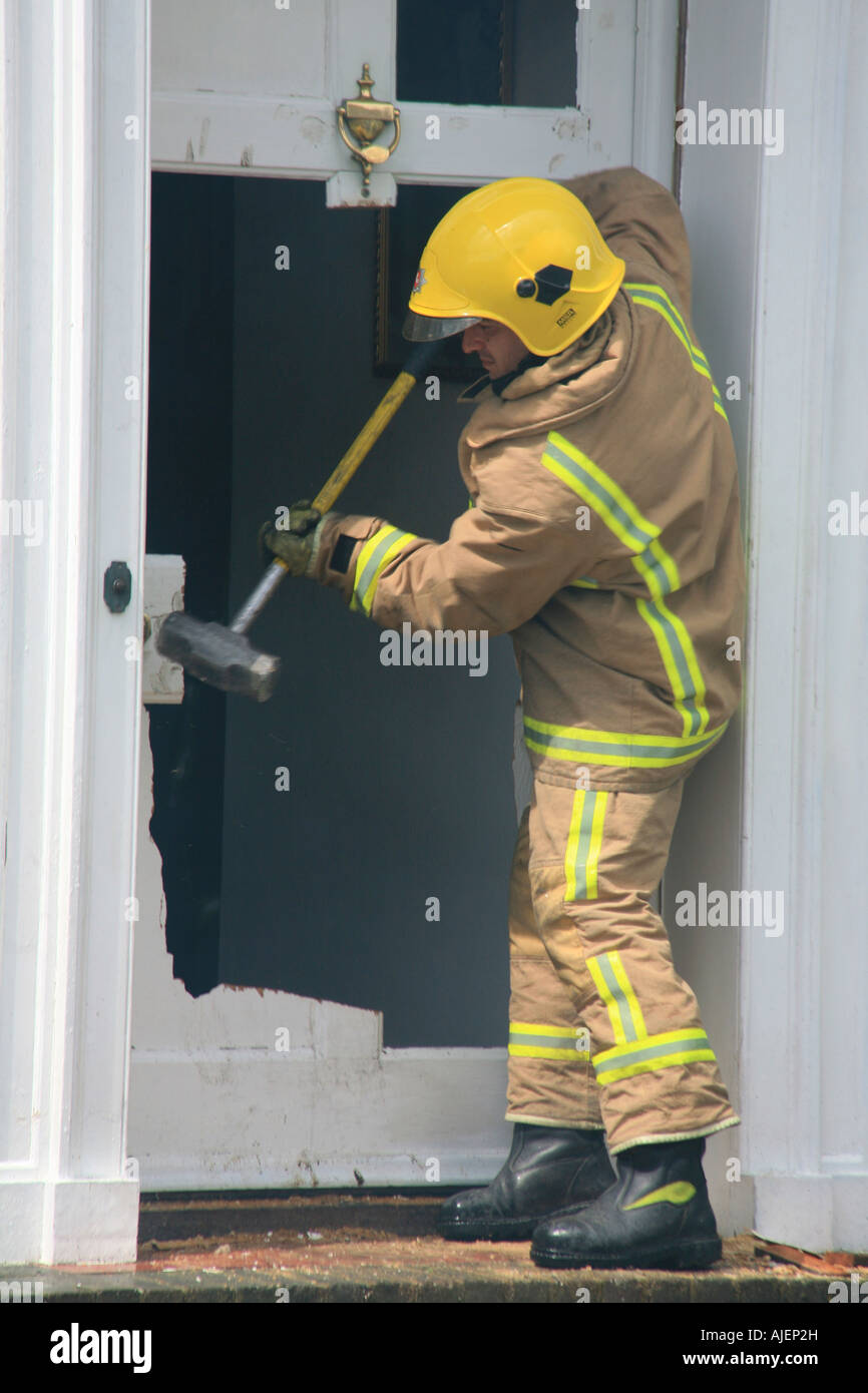 Feuerwehrmann eine Haustür umzuwerfen, Zugriff auf eine Housefire in Tunbridge Wells Kent England Großbritannien Stockfoto