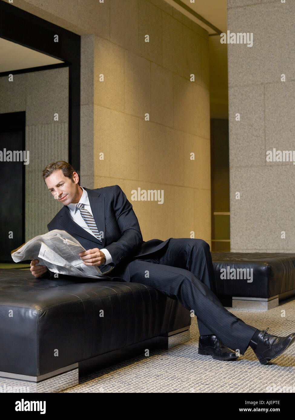 Geschäftsmann lesen Zeitung in der lobby Stockfoto