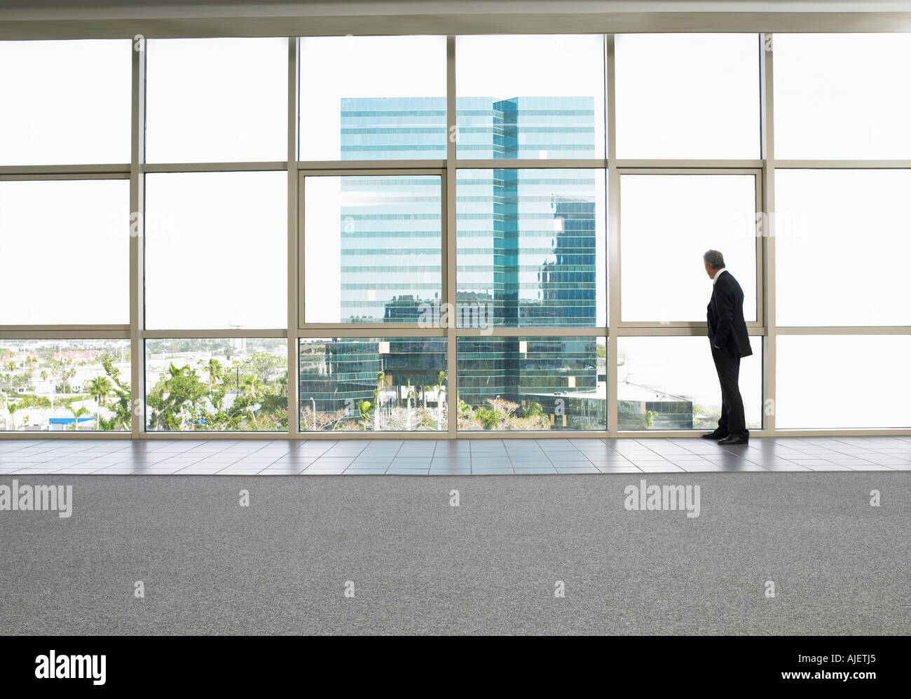 Geschäftsmann durch Fenster im Bürogebäude Stockfoto