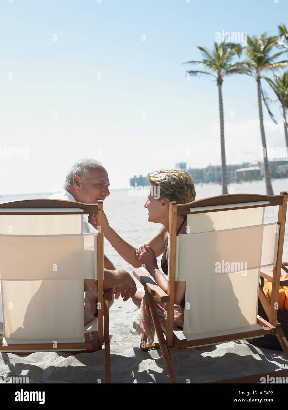 Älteres Paar auf Sonnenliegen am tropischen Strand, Rückansicht Stockfoto