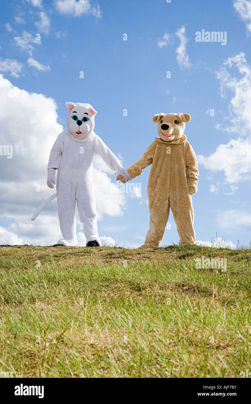 Menschen in Katzen- und Kostümen, die Hand in Hand Stockfoto