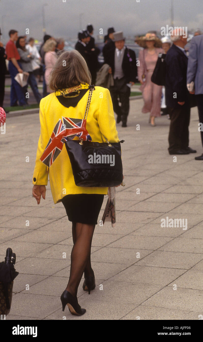 Derby Day Pferderennen racing Epsom Surrey England. Frau mit Union Jack-Flagge in Handtasche, gelbe Jacke. HOMER SYKES Stockfoto