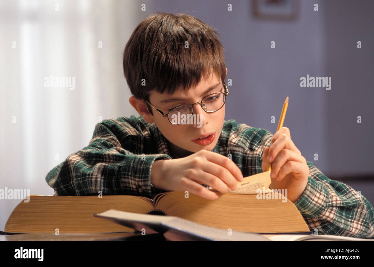 Nerdy Kaukasischen männlicher Student auf der Suche nach Wörtern in Unabridged Dictionary Stockfoto