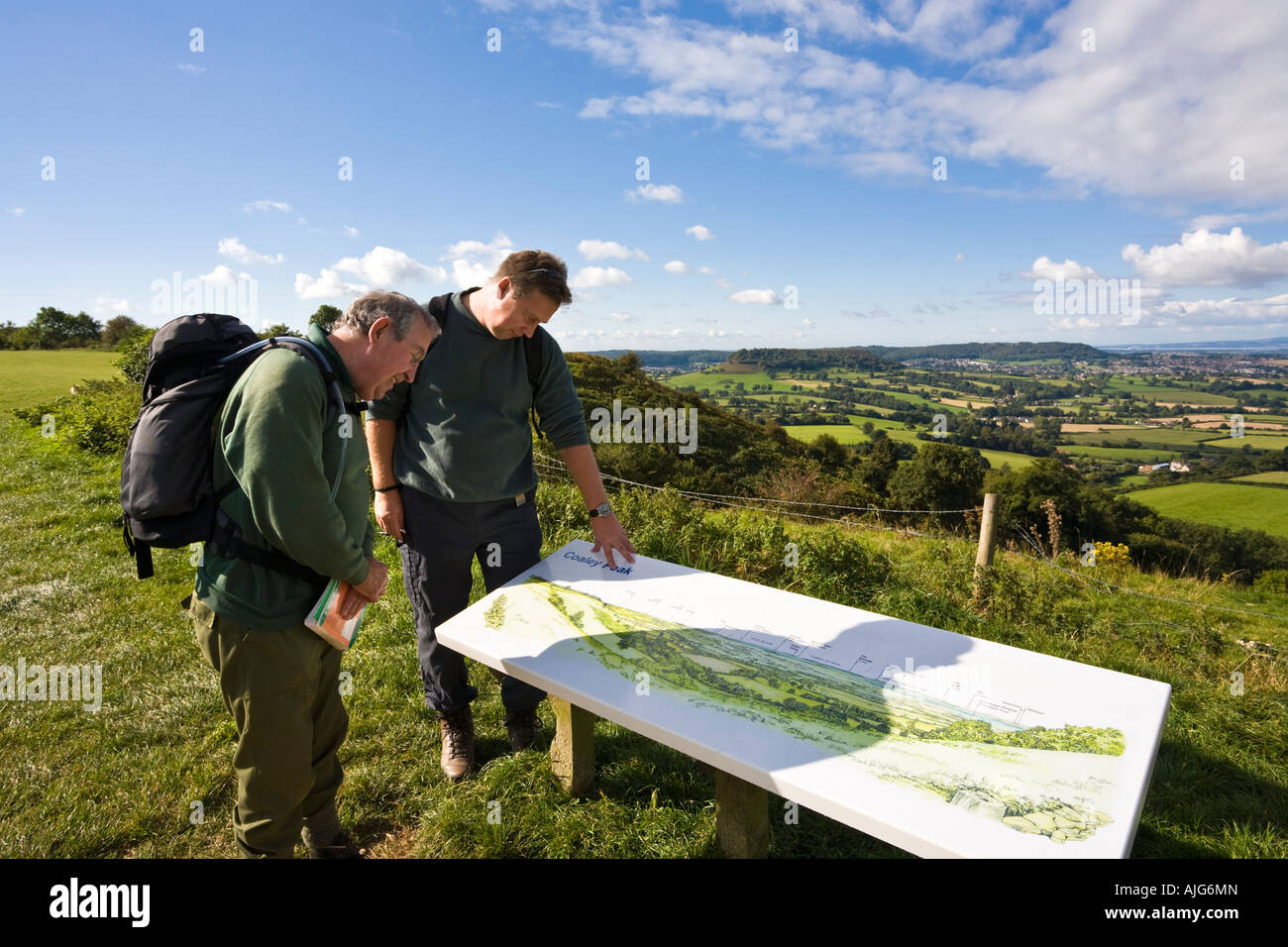Zwei Wanderer auf dem Cotswold Weg genießen den Blick über den Severn Vale aus Coaley Peak Picknickplatz, Gloucestershire Stockfoto