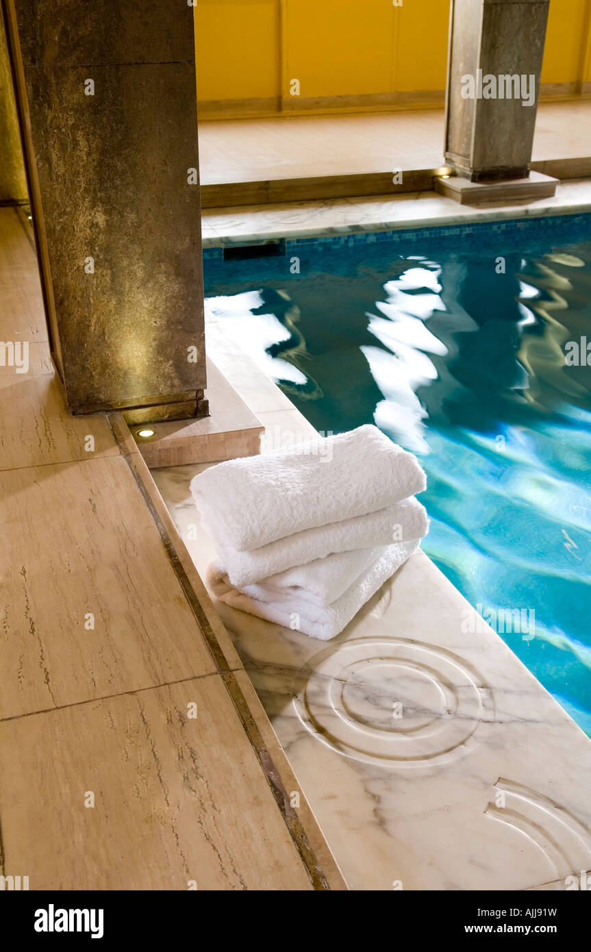 Gefaltete Handtücher auf geschnitzten Marmor am Pool mit Kolonnaden Stockfoto