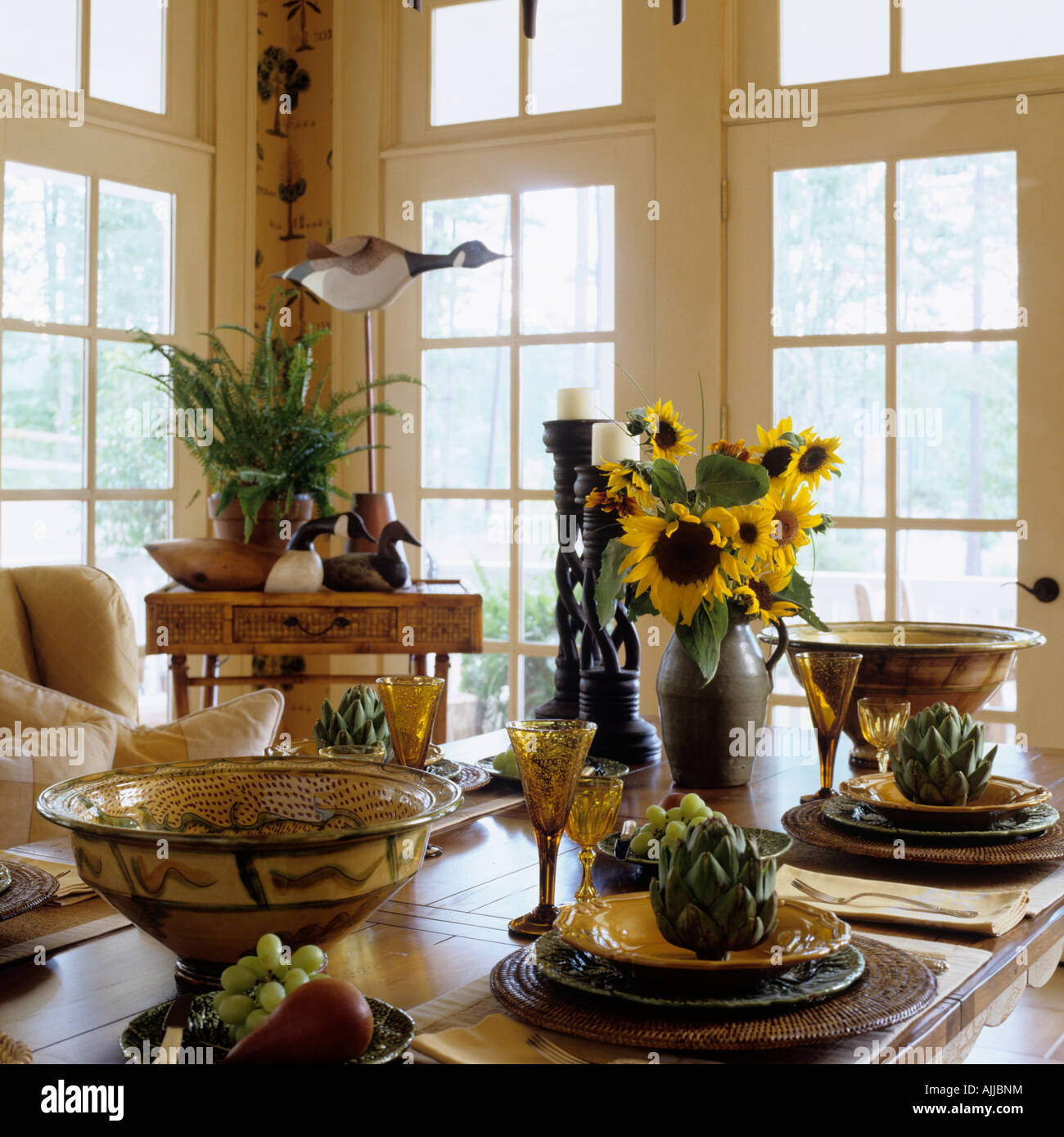 Esstisch mit Keramikschalen und dekorative Artischocken und Sonnenblumen Stockfoto