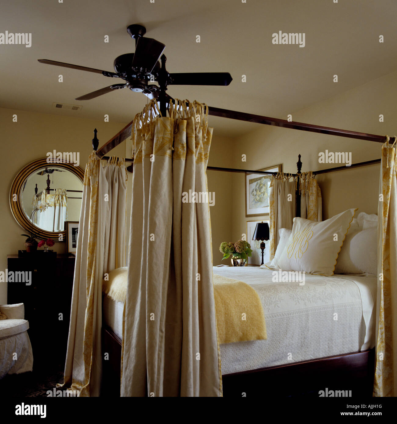 Schlafzimmereinrichtungen Bett mit Gardinenstange im Schlafzimmer mit  runder Spiegel und Deckenventilator Stockfotografie - Alamy