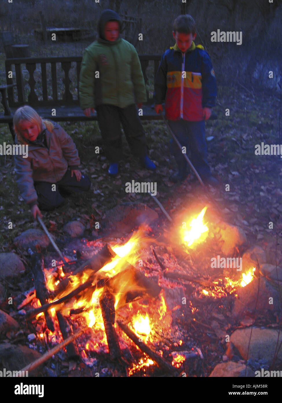 Kinder machen ein Lagerfeuer und stossen in es Stockfoto