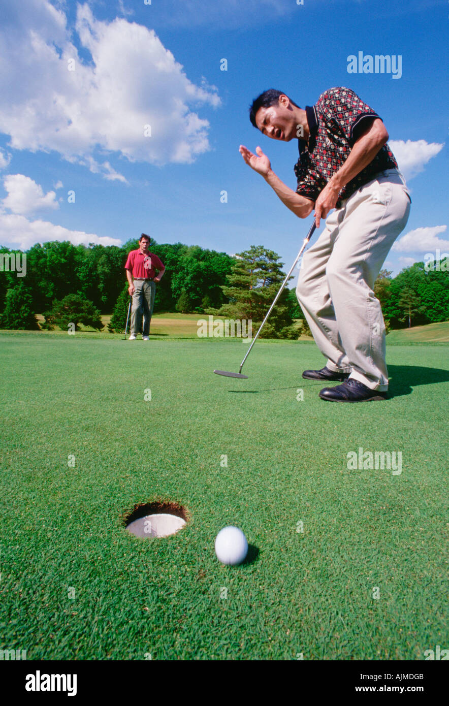 Golfer, Kriecherei, nachdem er keinen Putt zu versenken Stockfoto