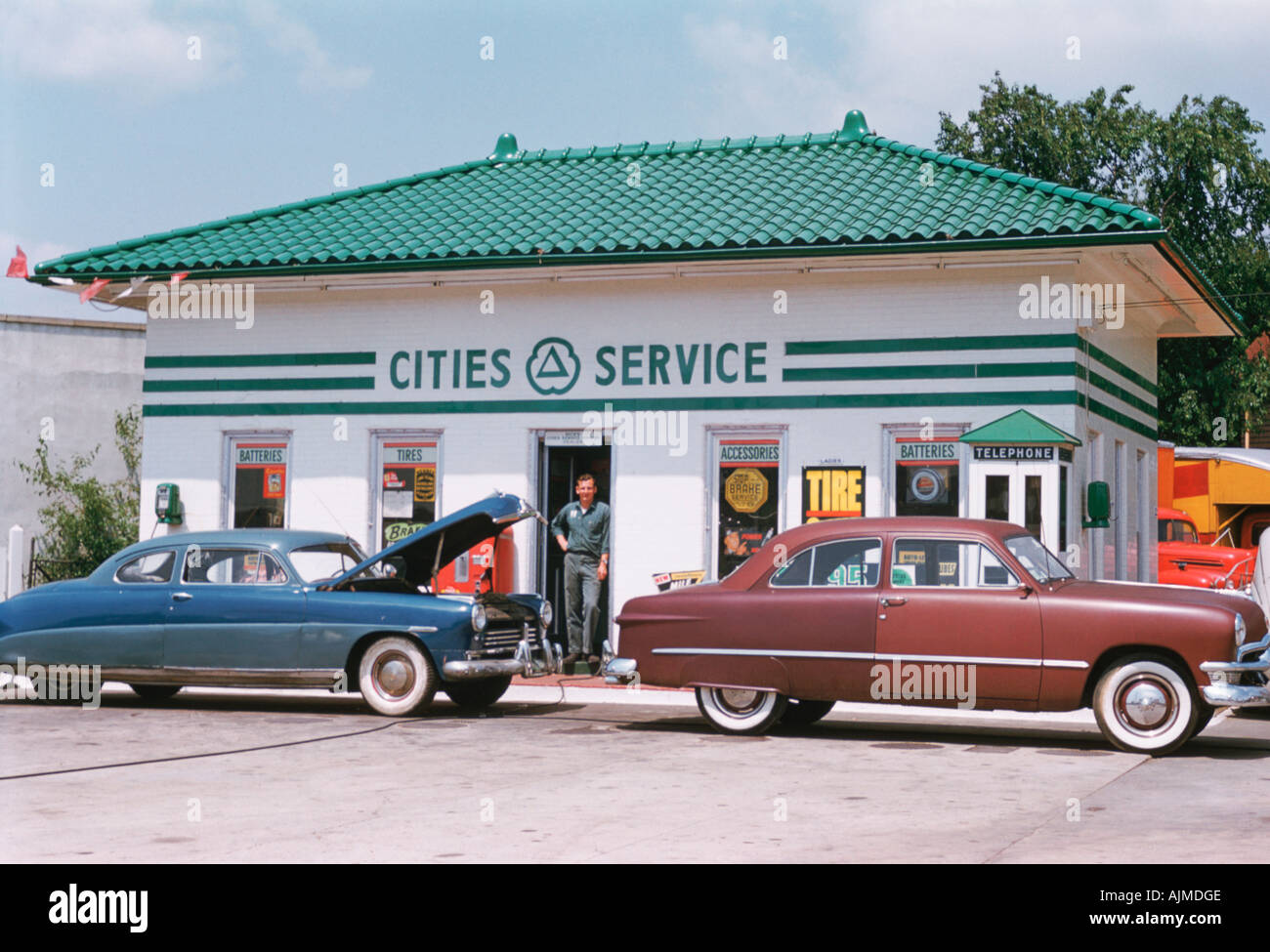 Zwei klassische Autos an einer Tankstelle in den 1950er Jahren Stockfoto