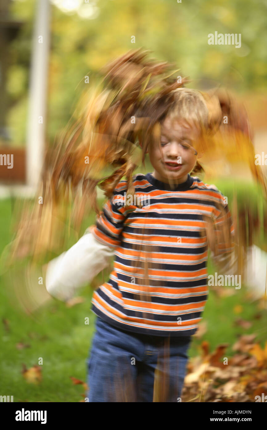 Kleiner Junge spielt mit Herbstlaub Stockfoto