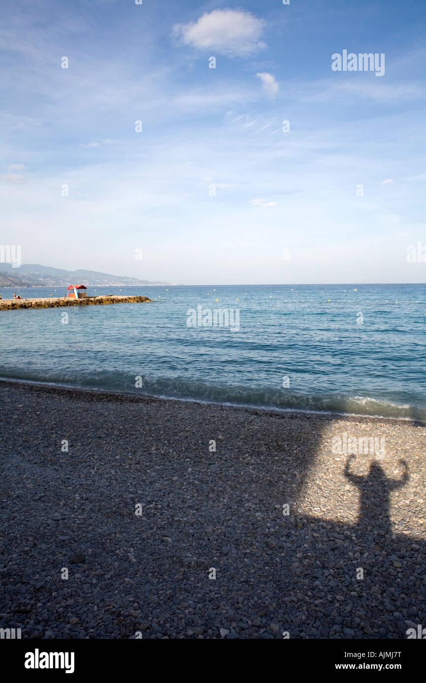 Schatten springen Person auf einem Kiesstrand mit einem mediterranen Horizont. Sieger des Rennens, überglücklich. Sprung aus einer box Stockfoto