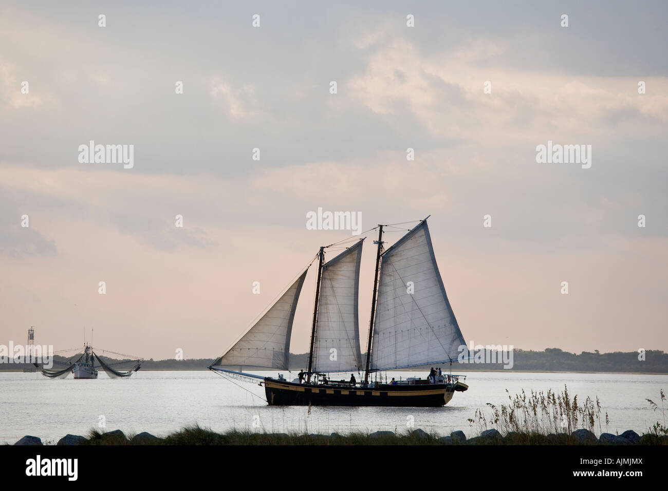 Amerikanischen Schooner Segelschiff mit Touristen, die Rückkehr in den Hafen bei Sonnenuntergang. Fischereifahrzeug im Hintergrund. Stockfoto