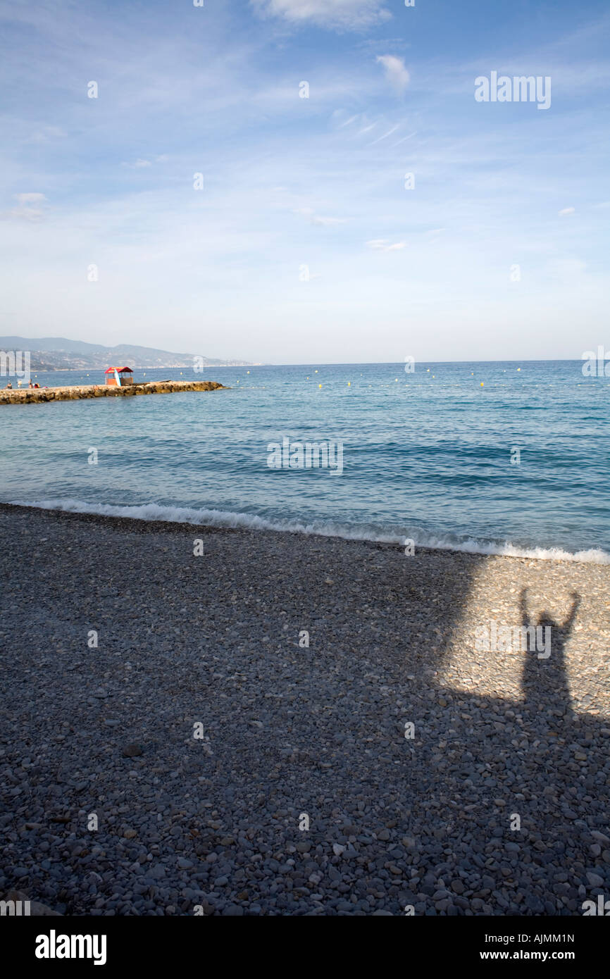 Schatten springen Person auf einem Kiesstrand mit einem mediterranen Horizont. Sieger des Rennens, überglücklich. Sprung aus einer box Stockfoto