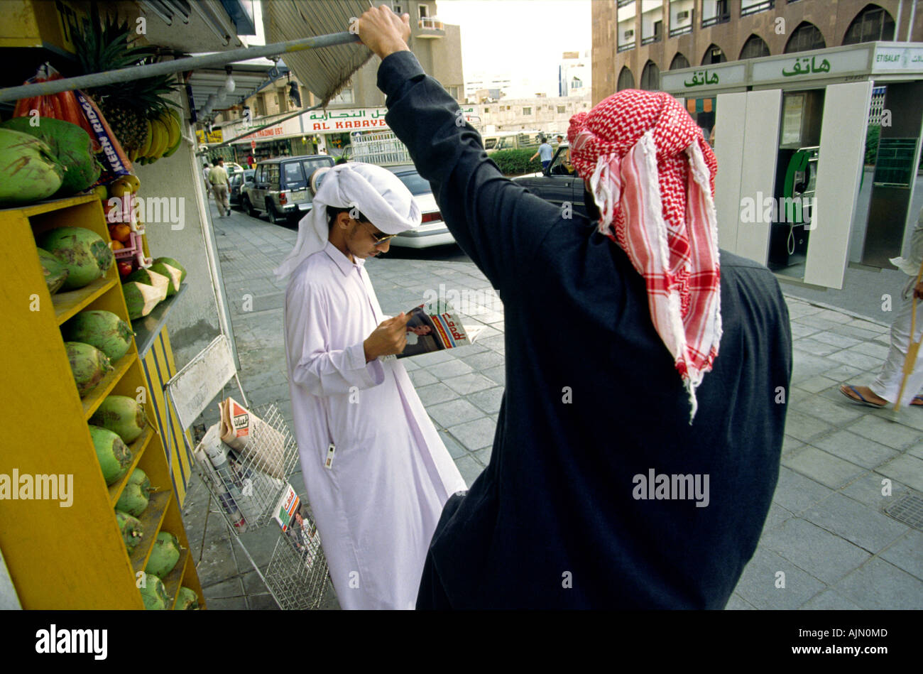 VAE Dubai arabische Männer lesen Magazin auf Straße Stockfoto