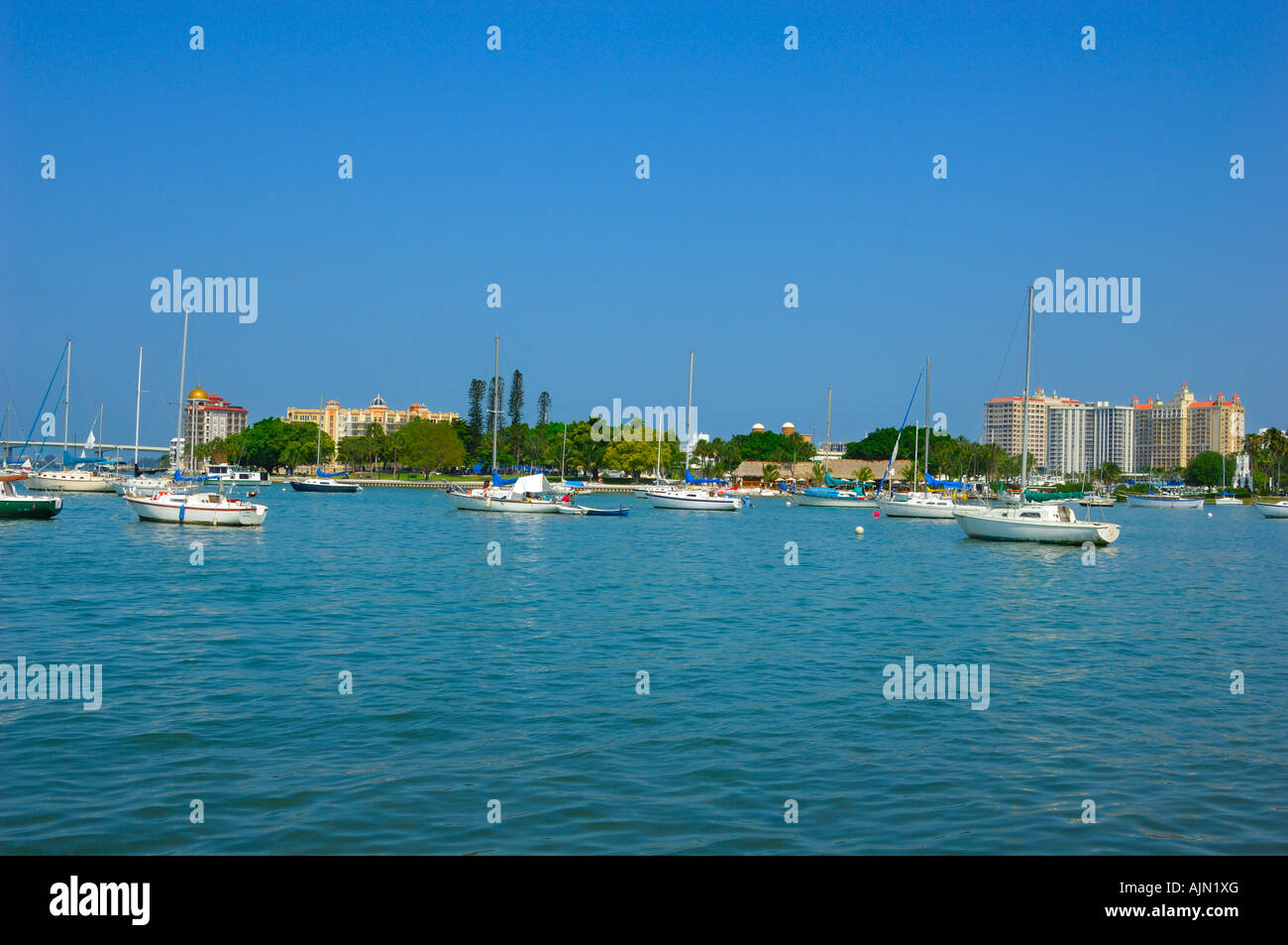 Boote in kleinen Lagune am Meer Sarasota Bay front Sarasota Florida mit strohgedeckten Restaurant Gebäude hinter und üppigen exotischen Palmen t Stockfoto