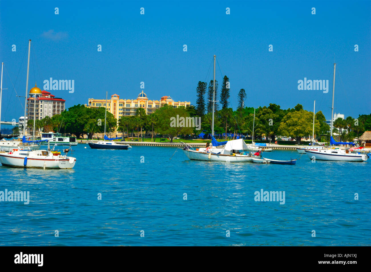 Boote in kleinen Lagune am Meer Sarasota Bay front Sarasota Florida mit strohgedeckten Restaurant Gebäude hinter und üppigen exotischen Palmen t Stockfoto