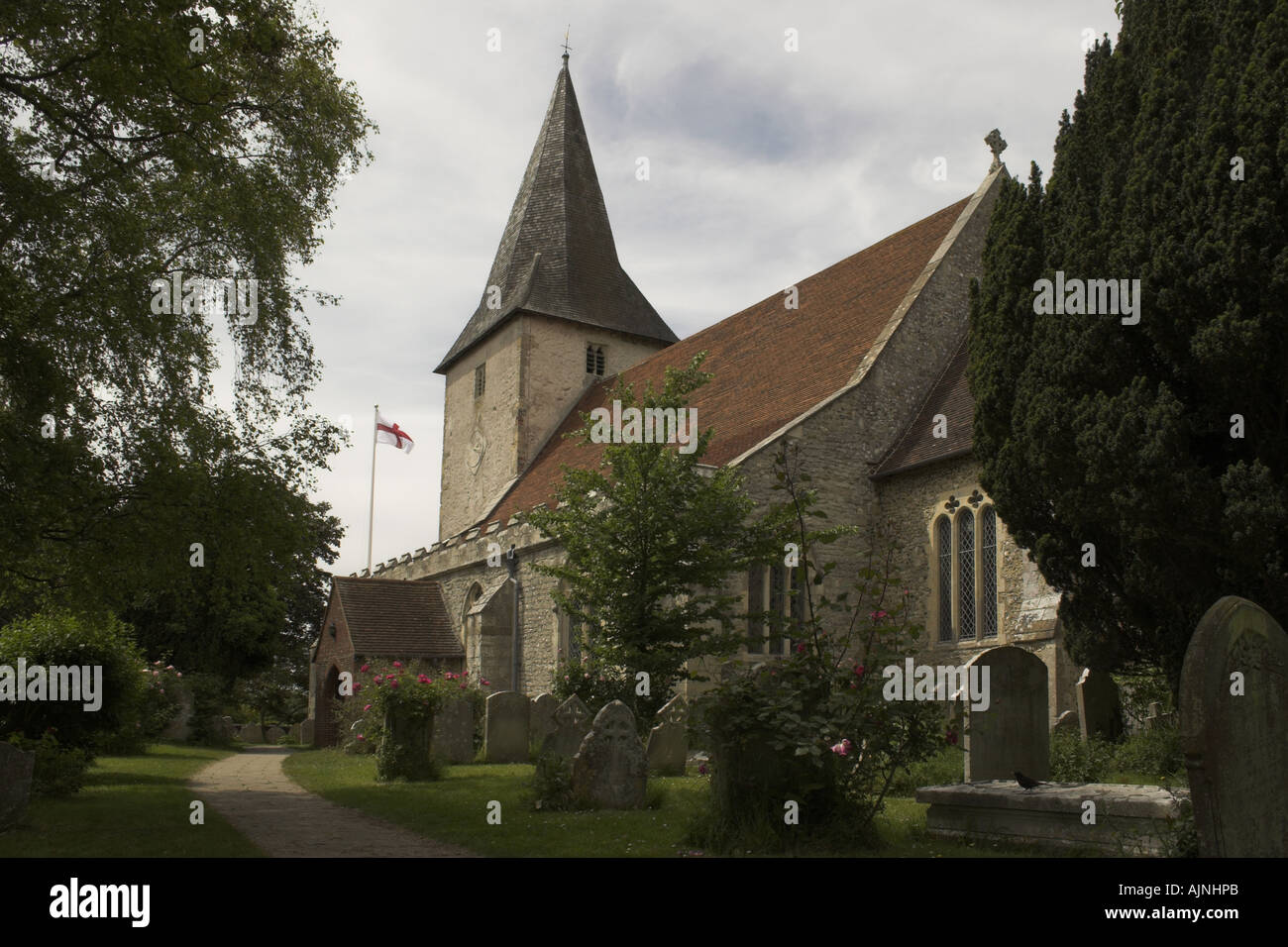 Holy Trinity Church, High Street, Bosham, West Sussex, England, UK - Flagge von St. George fliegt im Hintergrund Stockfoto