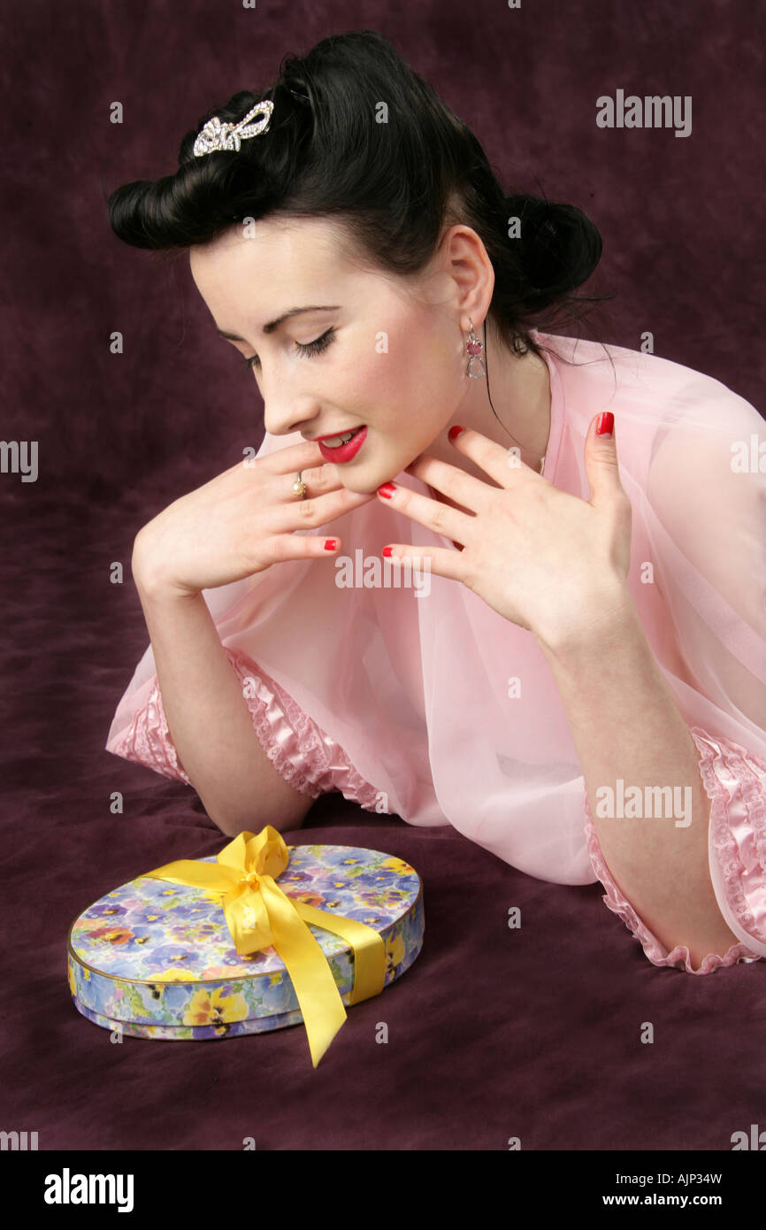 Pin Up Girl in einem rosa Kleid mit einem Feld von Candy mit einer gelben Schleife gebunden Stockfoto