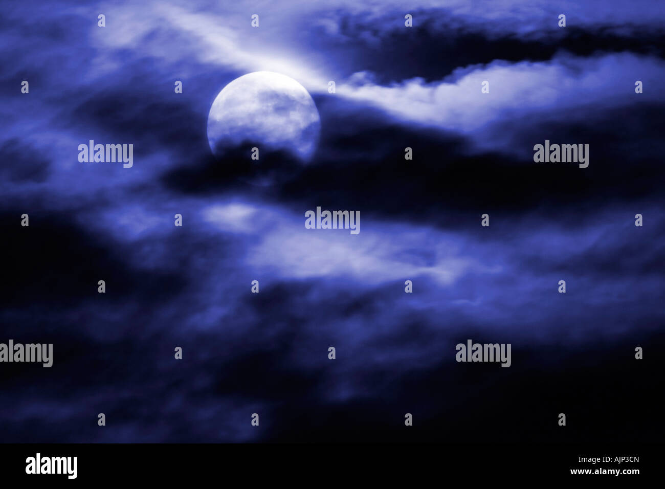 Mond von Wolken in einem nachtblauen Himmel teilweise verdeckt Stockfoto