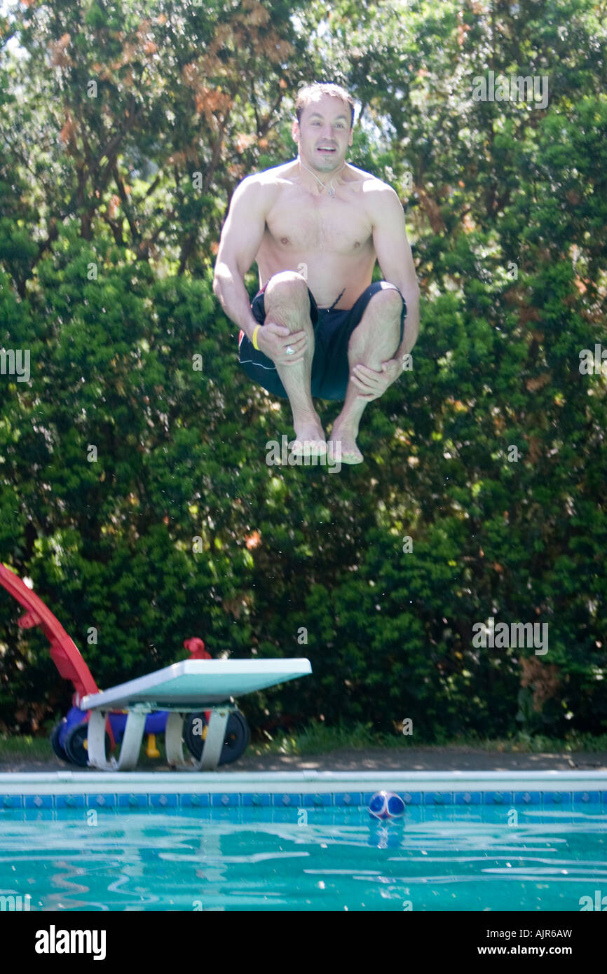 Mann springt in Pool tun eine Kanonenkugel in seinen Badeanzug Stockfoto