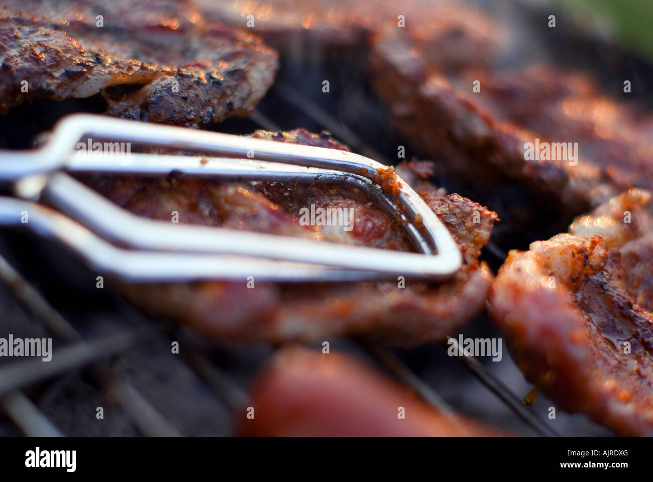 Delicious chuck Steaks auf dem Grill Detail mit Metall Zange geringe Schärfentiefe Stockfoto