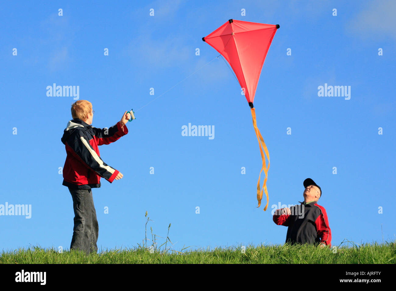 ein Großvater und sein Enkel fliegen einen Drachen zusammen Stockfoto