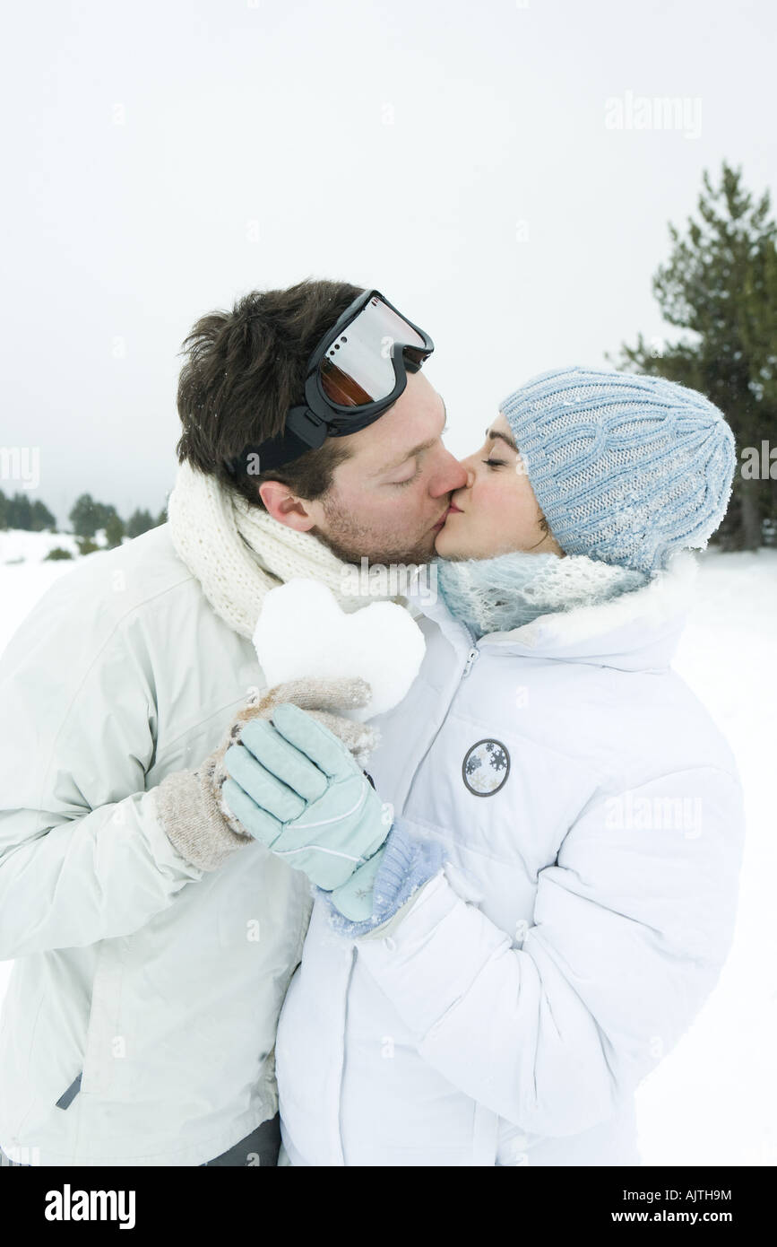 Junges Paar küssen, hält Herz aus Schnee zusammen gemacht, die Augen geschlossen, Porträt Stockfoto