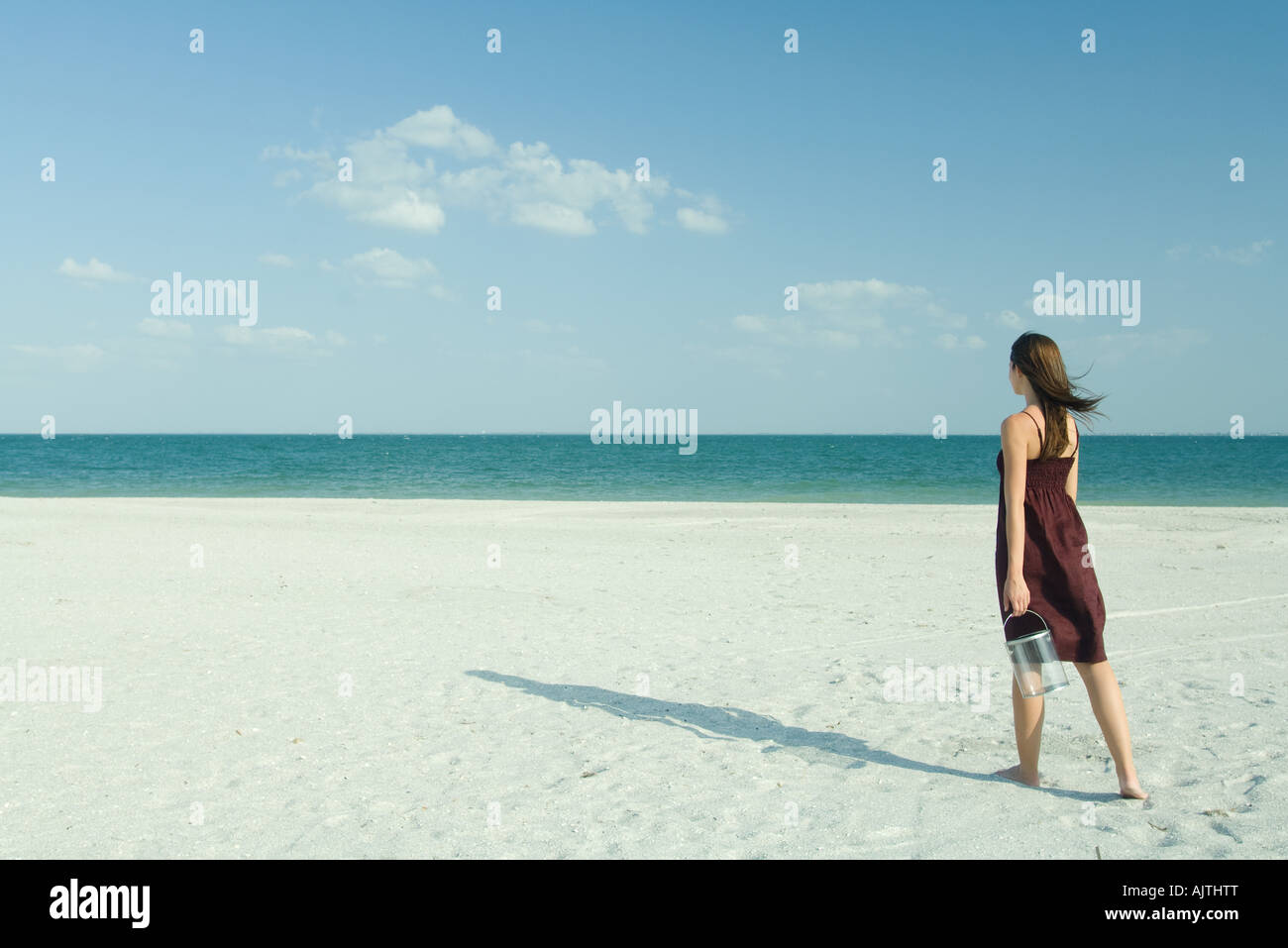 Frau, die zu Fuß über den Strand, die durchsichtigen Behälter, Ganzkörperansicht, Rückansicht Stockfoto