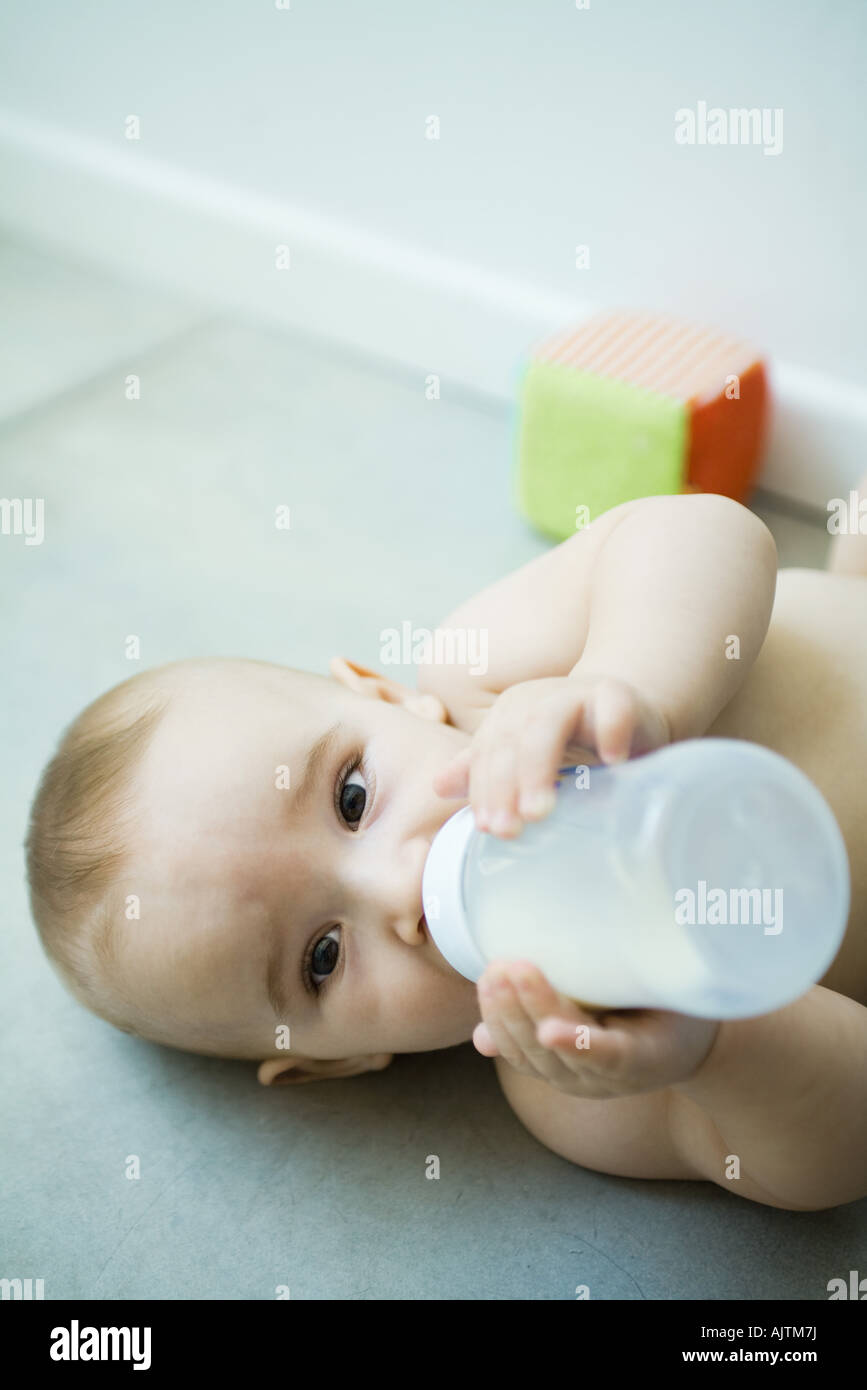 Baby auf Boden liegend, trinken aus der Flasche Stockfoto