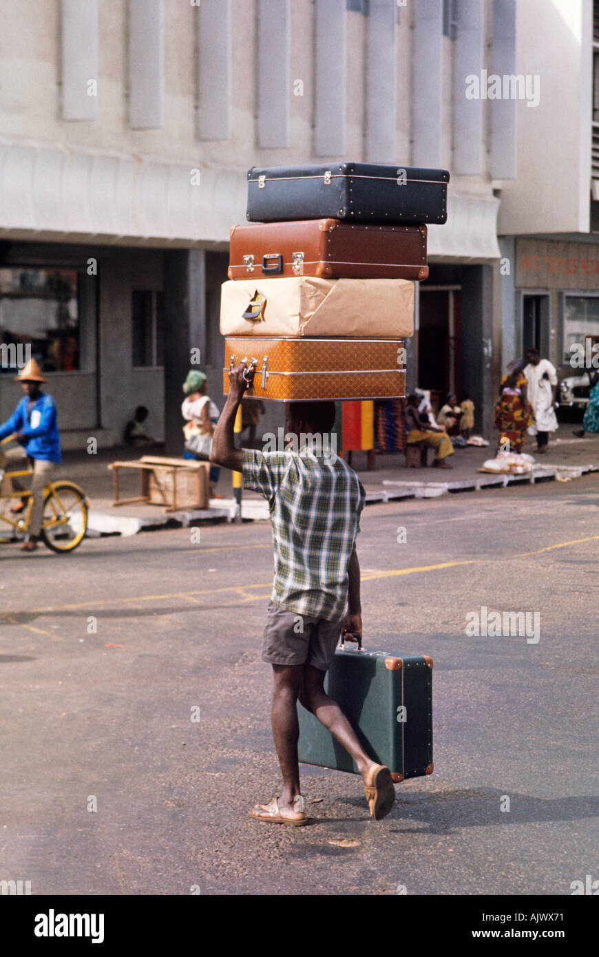 In Accra Ghana kreuzt verkaeufers Koffer eine Straße mit seinem Bestand auf seinem Kopf Stockfoto