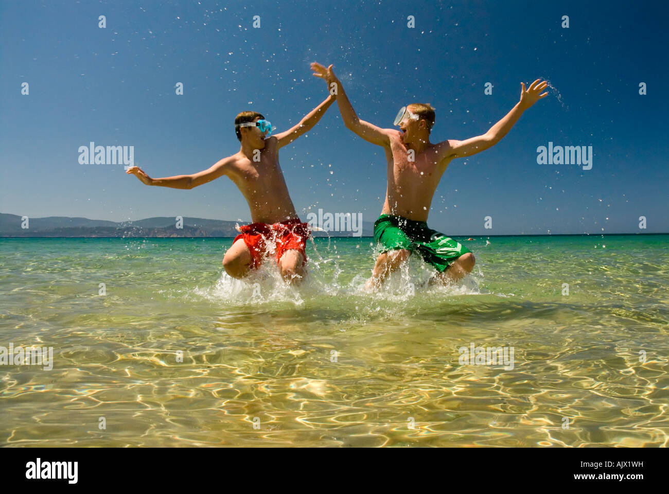 Zwei Jungs im Teenageralter spielen im flachen Wasser auf sandigen Strand Luke Hanna Oscar Hanna MR Stockfoto