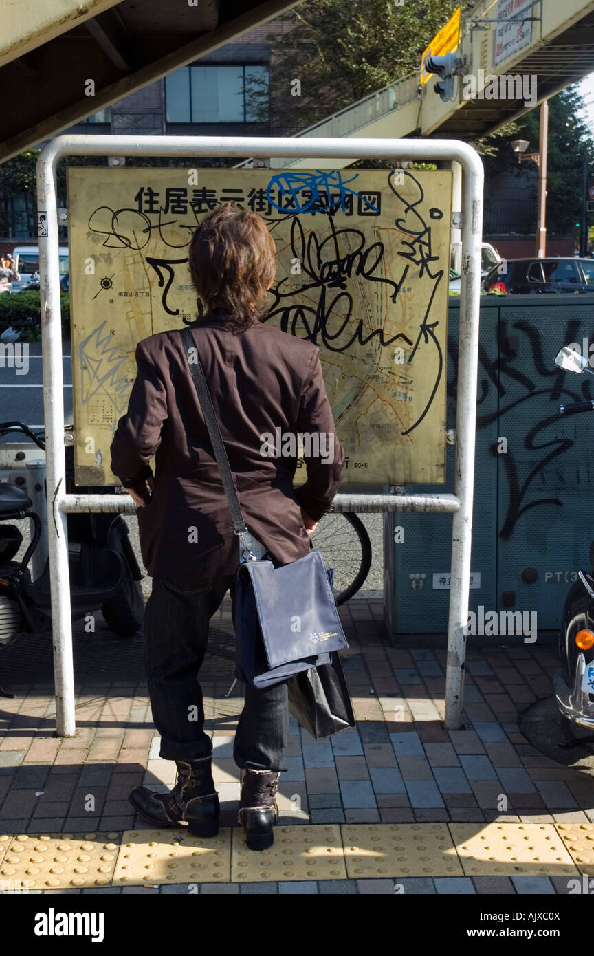 Mann überprüfen eine Map, die mit Graffiti Harajuku Tokio behandelt worden Stockfoto