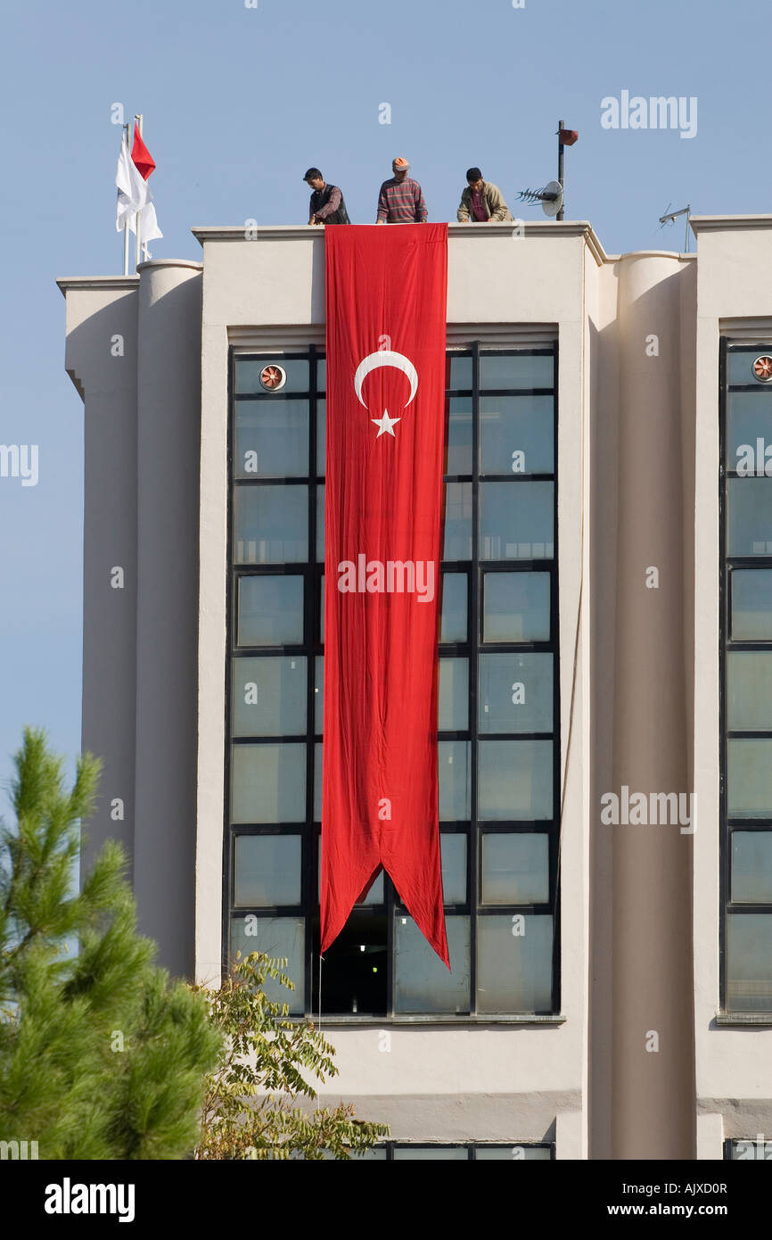 Männer, die Montage eine große Fahne auf öffentliche Gebäude in der Türkei Stockfoto