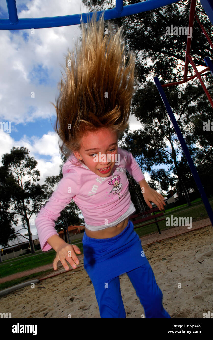 junge weibliche Kind tun Backflip mit Haaren stehen senkrecht, bewölkten blauen Himmel im Hintergrund, Hochformat Stockfoto