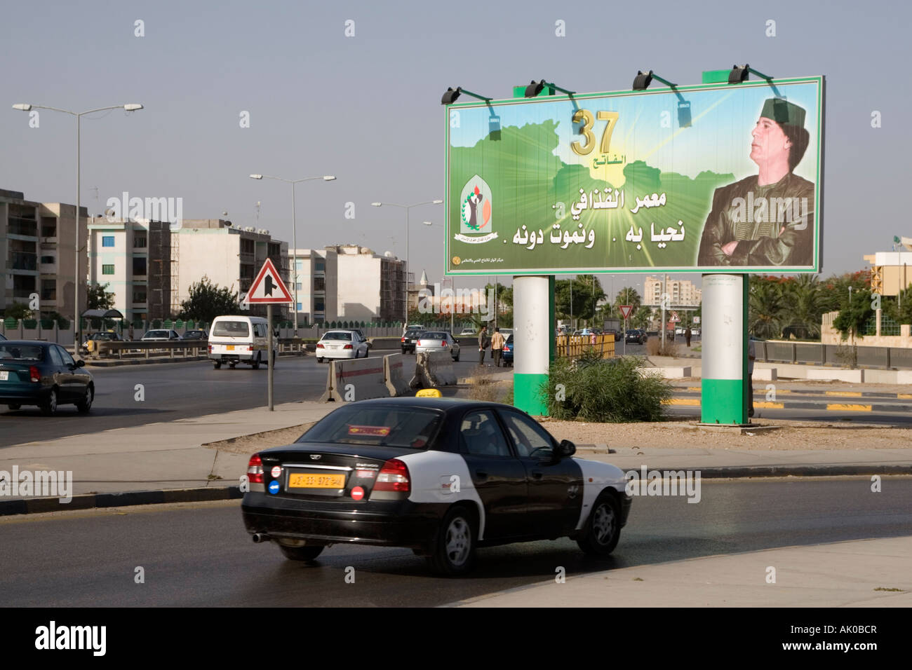 Tripoli, Libyen. Straßenszene, Gaddafi Billboard, 37. Jahrestag der Revolution, Taxi Stockfoto